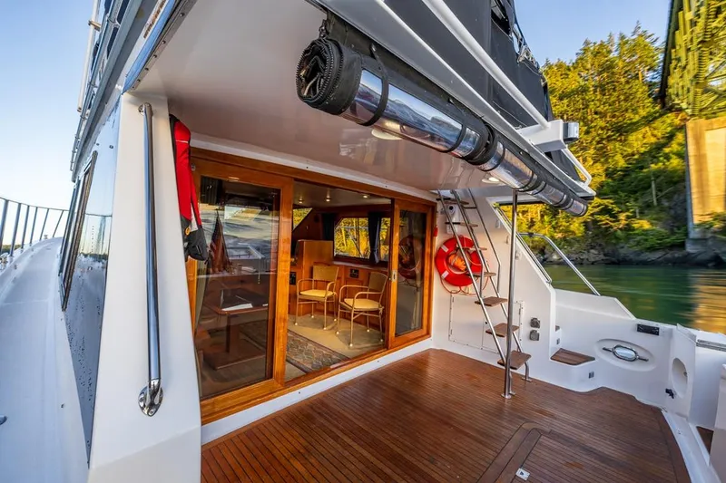 Slide: The Image of 1990 Ocean Alexander 48 Cockpit Motoryacht with wooden deck and glass doors, docked near greenery. - 40