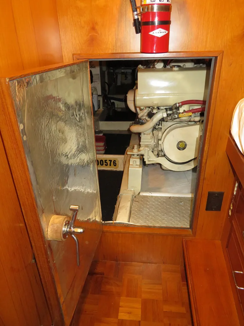 Slide: The Image of Engine room access on 1990 Ocean Alexander 48 Cockpit Motoryacht, featuring wooden interior and fire extinguisher. - 49