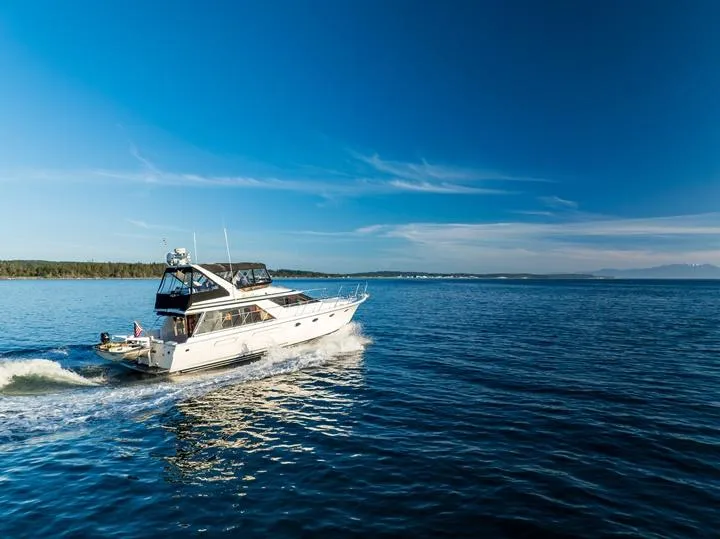 Slide: The Image of 1990 Ocean Alexander 48 Cockpit Motoryacht cruising on open water under clear blue skies. - 12
