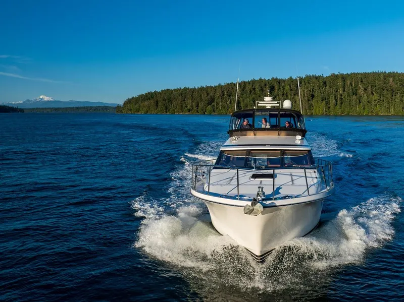 Slide: The Image of 1990 Ocean Alexander 48 Cockpit Motoryacht cruising on a scenic lake with forested shoreline. - 18