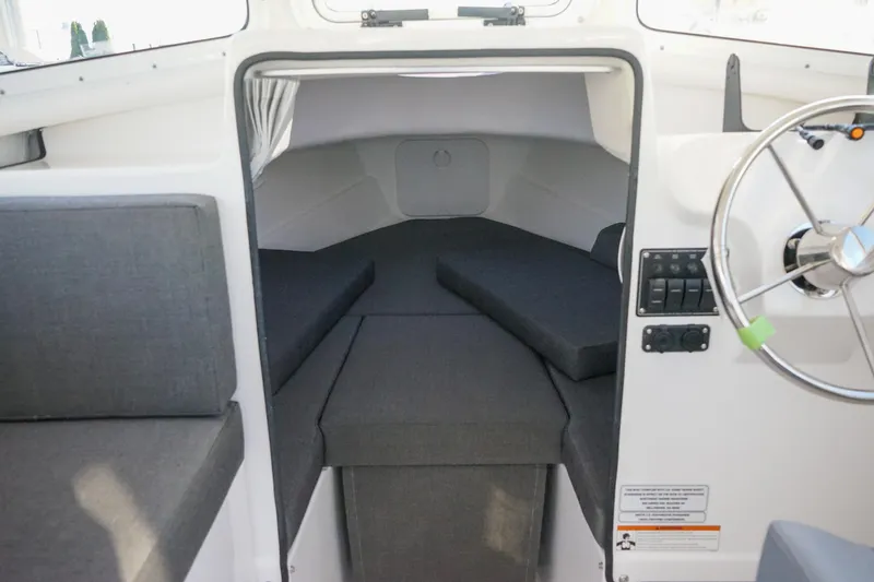 Slide: The Image of 2025 C-Dory 22' Cruiser interior cabin with seating and steering wheel. - 12
