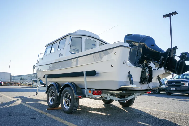 Slide: The Image of 2025 C-Dory 22' Cruiser on trailer, parked outdoors, showcasing sleek design and powerful engine. - 14