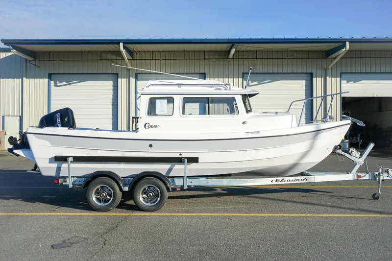 Slide: The Image of 2025 C-Dory 22' Cruiser on trailer, parked outside a warehouse. - 5