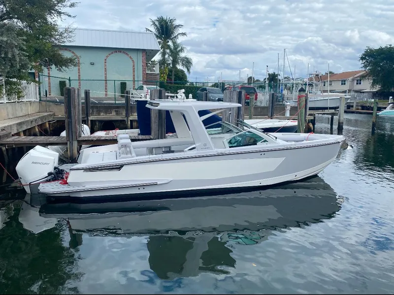 The Image of 2024 Aviara AV32 OB boat docked in a marina, surrounded by calm water. - 1