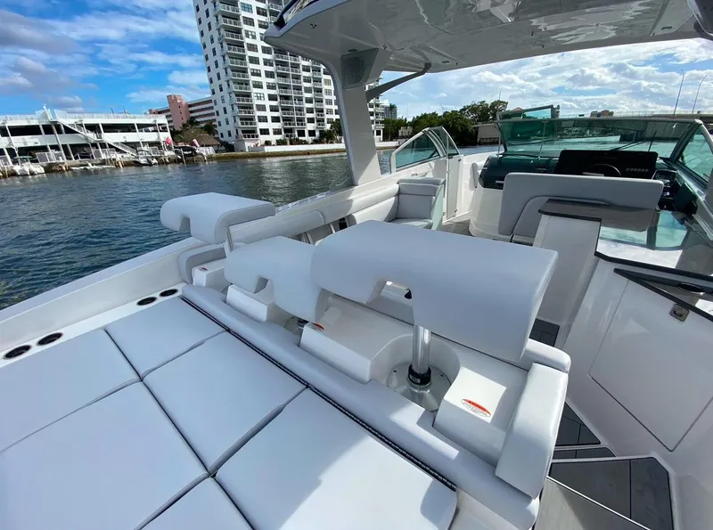 Slide: The Image of 2024 Aviara AV32 OB luxury boat with white seating, docked near waterfront buildings. - 5