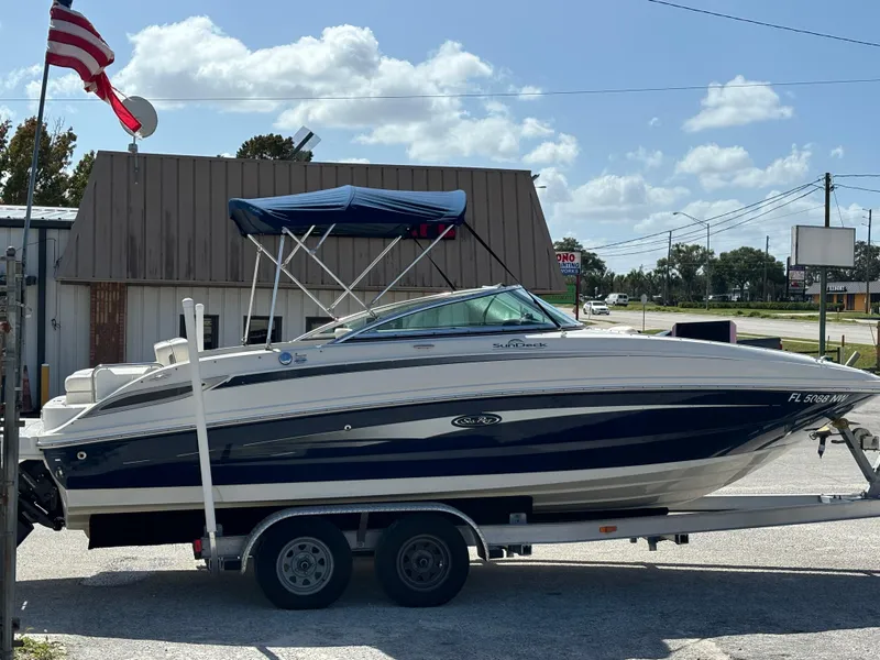 Slide: The Image of 2008 Sea Ray 230 Sundeck boat on trailer, parked outdoors under a blue sky. - 2