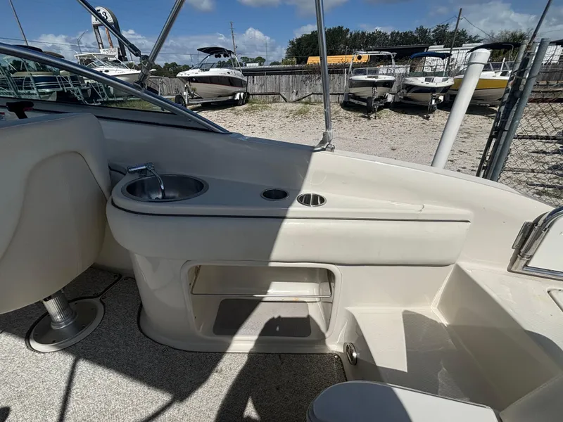 Slide: The Image of 2008 Sea Ray 230 Sundeck interior with sink and storage, docked outdoors. - 25