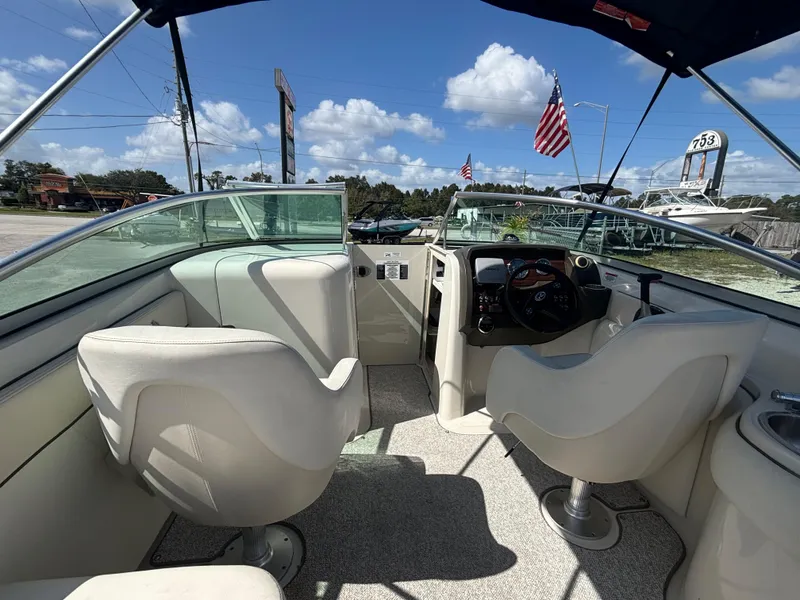 Slide: The Image of 2008 Sea Ray 230 Sundeck interior with steering wheel and seating under blue sky. - 26