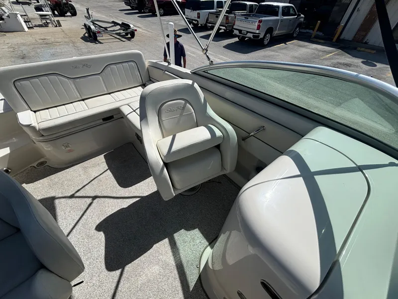 Slide: The Image of 2008 Sea Ray 230 Sundeck interior with seating and dashboard, parked in a marina. - 37