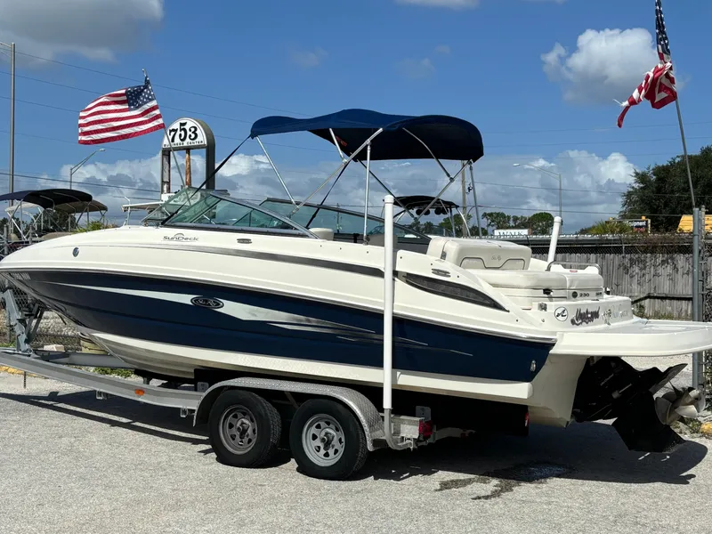 Slide: The Image of 2008 Sea Ray 230 Sundeck boat on trailer, blue canopy, American flags in background. - 4