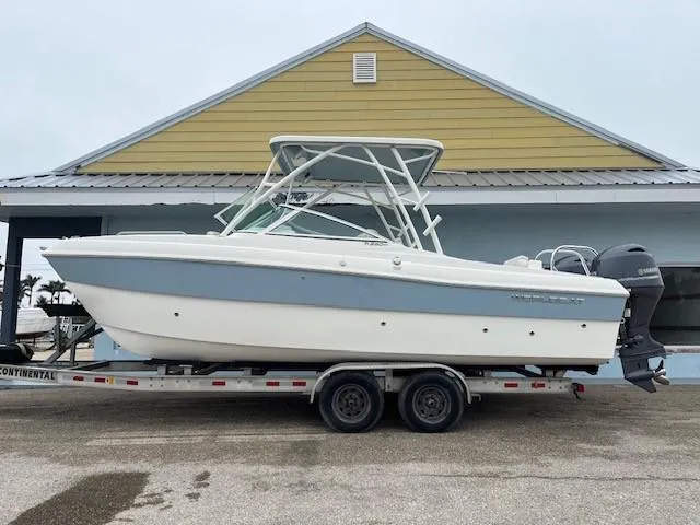 Slide: The Image of 2025 World Cat 230 SD boat on trailer, parked outside a building. - 1