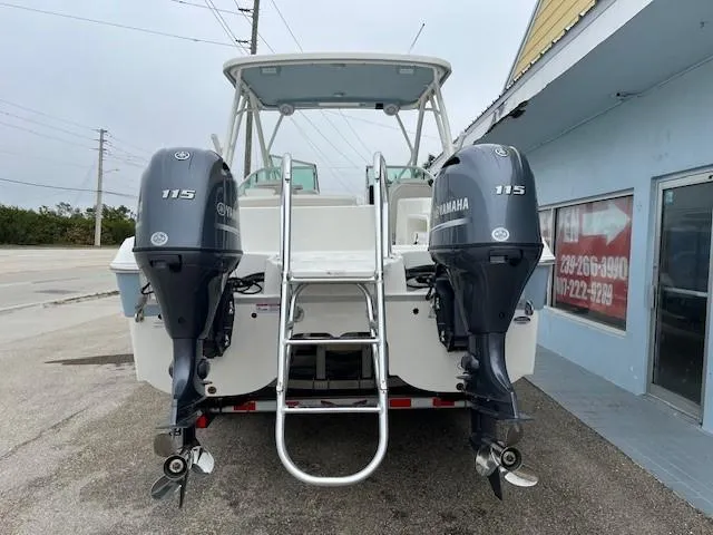 Slide: The Image of 2025 World Cat 230 SD boat with dual Yamaha 115 engines, parked near a building. - 2
