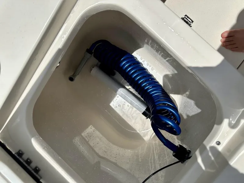 Slide: The Image of Storage compartment with coiled blue hose in 2023 Scout 215 Dorado boat. - 25
