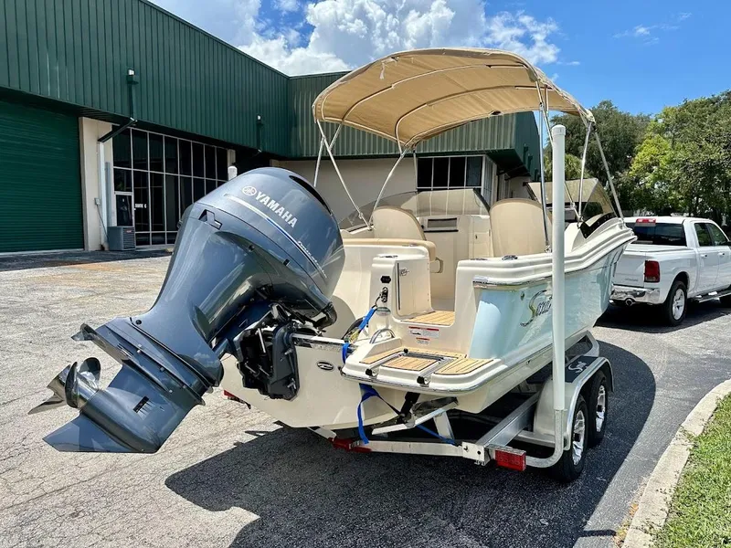 Slide: The Image of 2023 Scout 215 Dorado boat with Yamaha engine on trailer, parked outside a green building. - 4