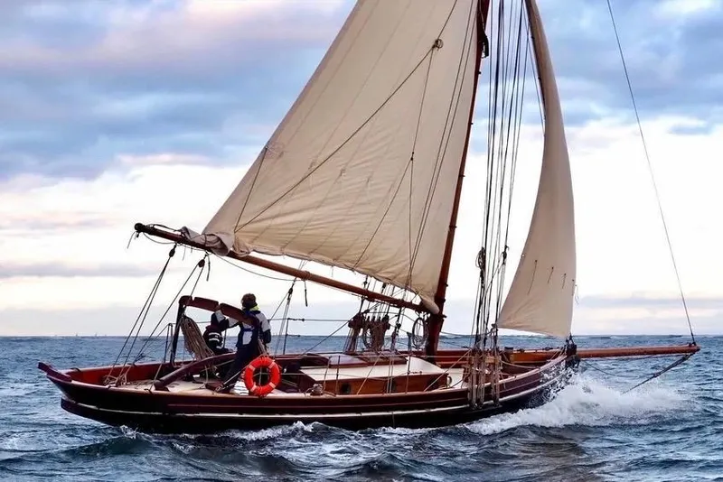 The Image of Vintage 1903 Morecambe Bay Prawner sailboat navigating ocean waves under a cloudy sky. - 1