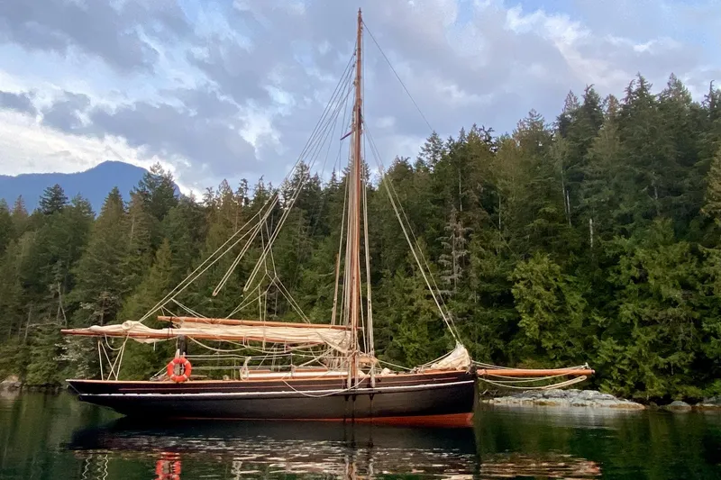 Slide: The Image of Vintage 1903 Morecambe Bay Prawner sailboat on tranquil water, surrounded by lush forest. - 14