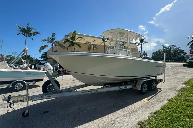 Slide: The Image of 2023 Sailfish 220 CC boat on trailer, parked outdoors under clear sky. - 1