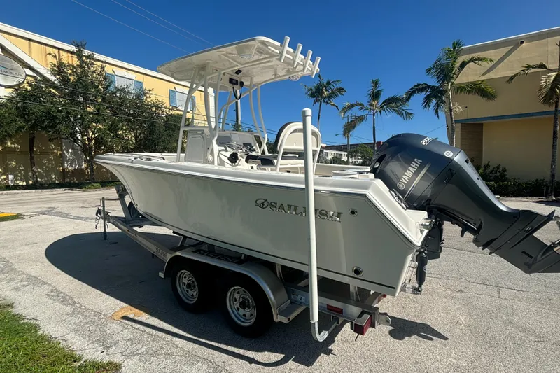 Slide: The Image of 2023 Sailfish 220 CC boat on trailer, parked outdoors under clear blue sky. - 2