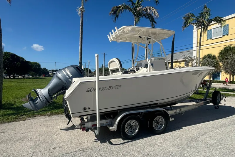 Slide: The Image of 2023 Sailfish 220 CC boat on trailer, parked outdoors under clear blue sky. - 3