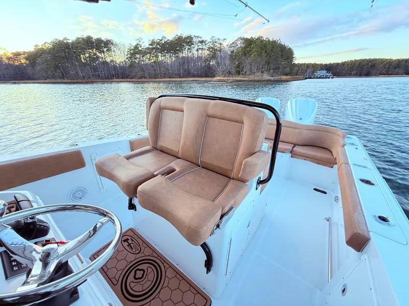 Slide: The Image of 2023 Sea Hunt Ultra 305 SE boat interior with tan seating on a serene lake. - 10