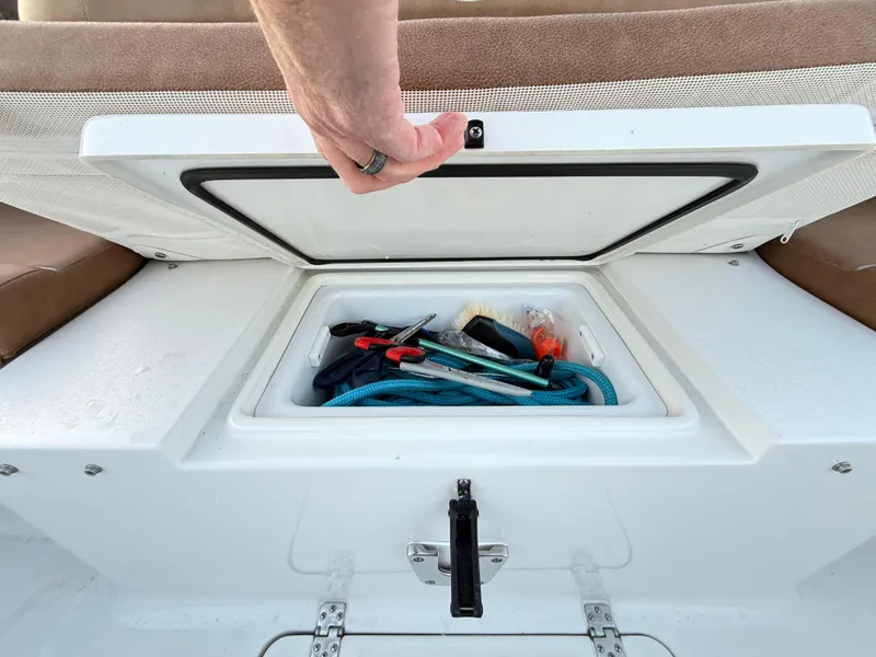 Slide: The Image of Storage compartment on 2023 Sea Hunt Ultra 305 SE boat with tools and rope. - 29