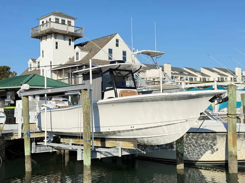 Slide: The Image of 2023 Sea Hunt Ultra 305 SE boat docked at a marina with coastal buildings. - 40