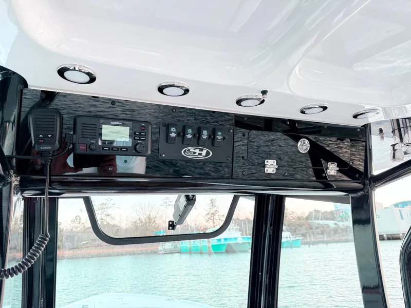 Slide: The Image of 2023 Sea Hunt Ultra 305 SE boat console with controls and radio. - 9