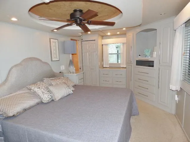 Slide: The Image of Cozy bedroom in a 2006 Thoroughbred 20x90, featuring elegant decor and a ceiling fan. - 11