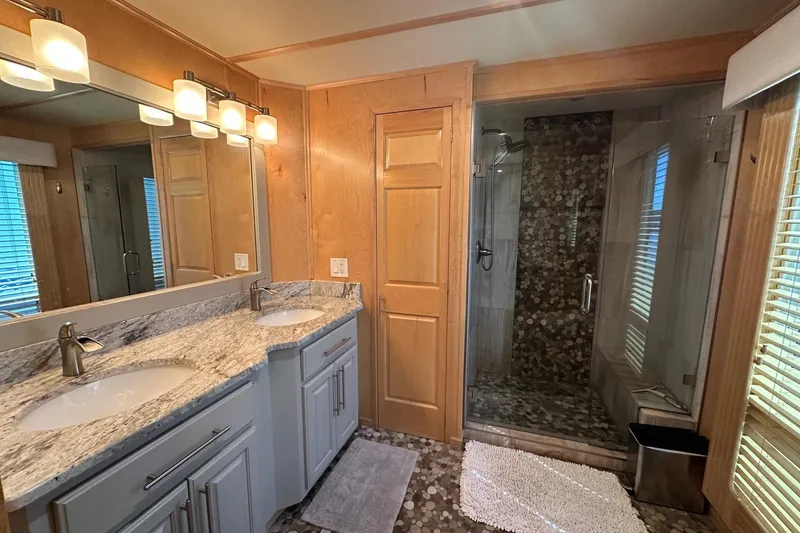Slide: The Image of Modern bathroom with dual sinks, granite countertop, and glass-enclosed shower in Thoroughbred 20x90 model. - 12