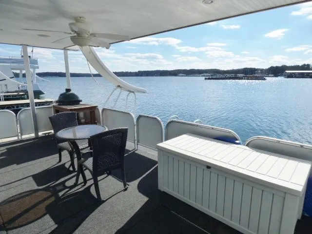 Slide: The Image of Upper deck of 2006 Thoroughbred 20x90 houseboat with lake view, table, chairs, and storage box. - 16