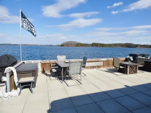 Slide: The Image of Spacious lakeside deck with seating, flag, and scenic water view under a blue sky. - 19