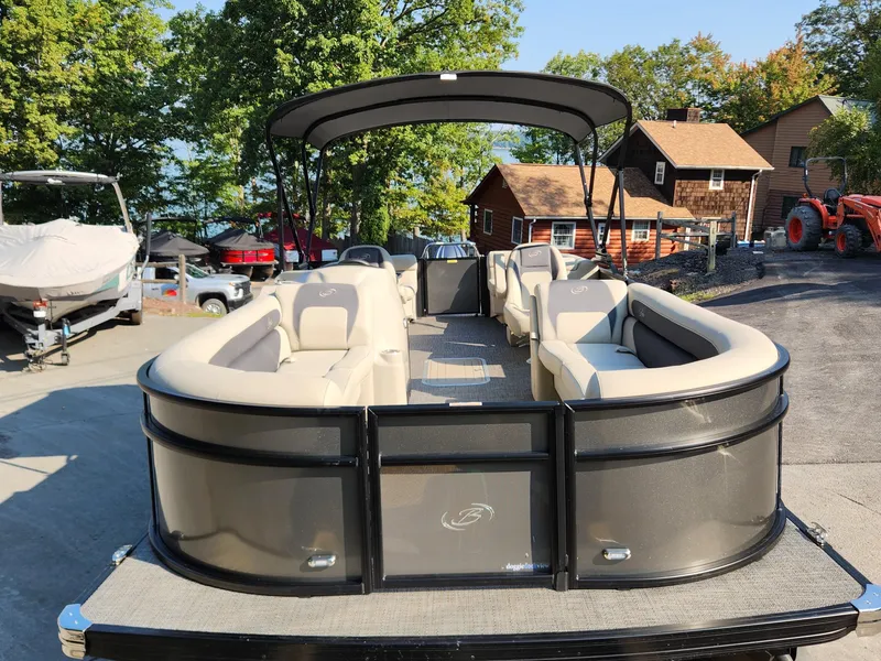 Slide: The Image of 2024 Barletta Aria 24QC pontoon boat with spacious seating, docked near rustic cabins. - 3