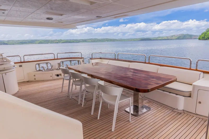 Slide: The Image of Luxury yacht deck with seating, wooden table, and scenic ocean view. Azimut 105 Grande, 2006 model. - 26