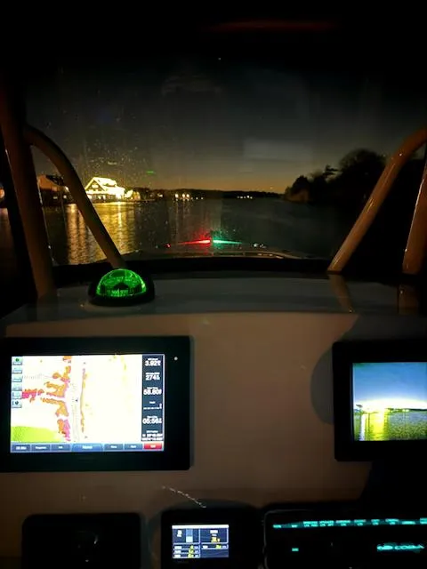 Slide: The Image of 2018 Cobia 277 Center Console boat dashboard at night with illuminated screens. - 5