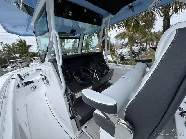 Slide: The Image of 2025 Blackfin 332cc boat cockpit with modern steering and seating, surrounded by palm trees. - 23