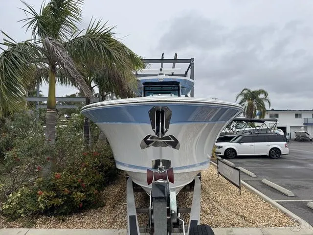 Slide: The Image of 2025 Blackfin 332cc boat on trailer, parked near palm trees in a lot. - 7