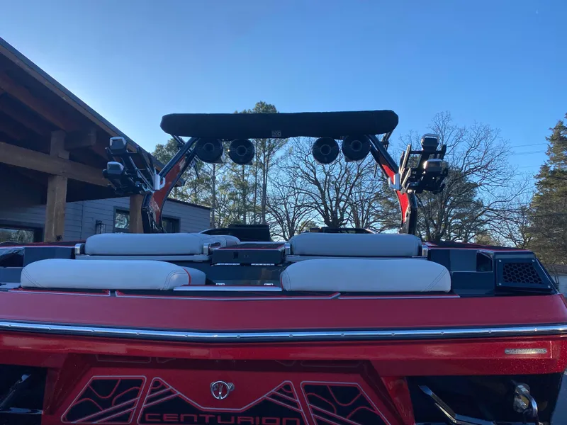 Slide: The Image of 2023 Centurion Fi23 boat, rear view with speakers and seating, under clear blue sky. - 2