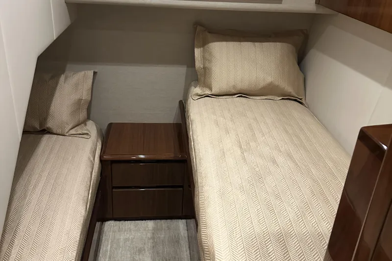 Slide: The Image of Twin beds in a 2017 Viking 55 Convertible yacht cabin with wooden nightstand. - 17