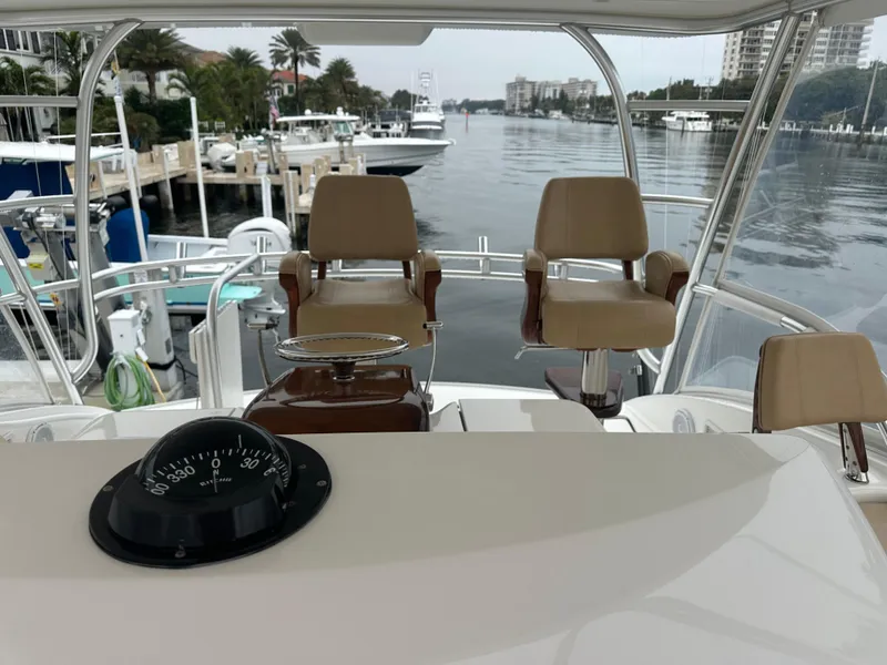 Slide: The Image of 2017 Viking 55 Convertible yacht helm with dual captain chairs, docked in a marina. - 2