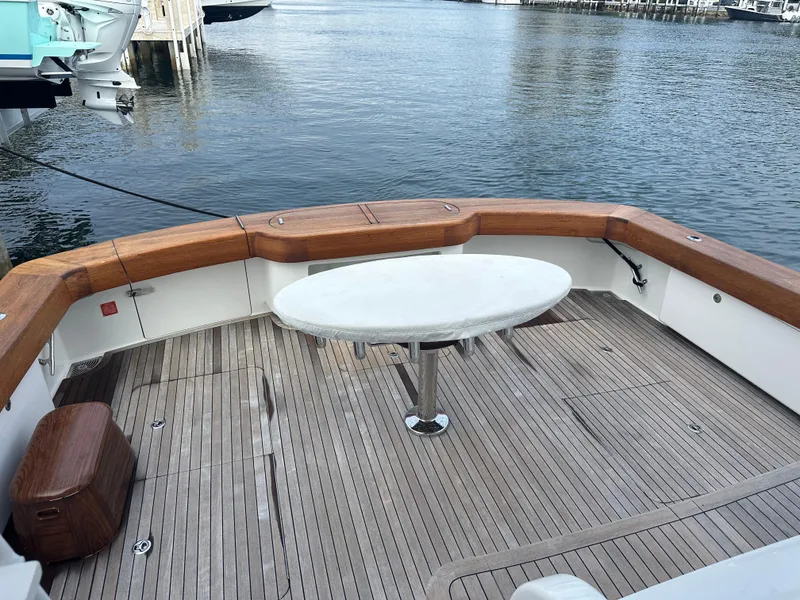 Slide: The Image of Viking 55 Convertible 2017 yacht deck with wooden flooring and oval table by the water. - 29