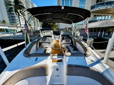 Slide: The Image of 2011 Yamaha Boats SX240 HO with spacious seating and canopy, docked near modern buildings. - 3