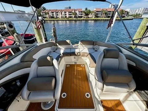 Slide: The Image of 2011 Yamaha Boats SX240 HO interior with plush seating and wooden deck, docked by waterfront. - 5