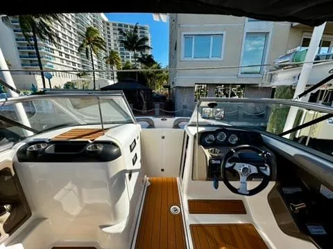 Slide: The Image of 2011 Yamaha Boats SX240 HO interior with modern dashboard and seating, docked near waterfront buildings. - 6