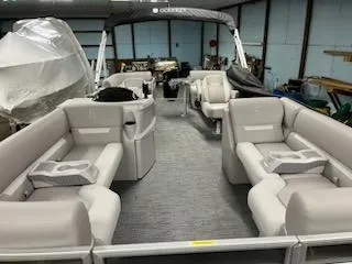 Slide: The Image of 2024 Sweetwater 2286SBCX pontoon boat with spacious seating and modern design in a storage facility. - 2