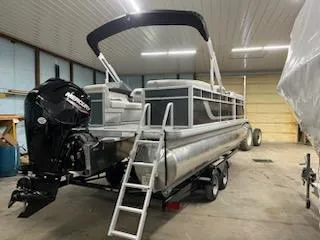 Slide: The Image of 2024 Sweetwater 2286SBCX pontoon boat in a garage, featuring a Mercury outboard motor. - 9