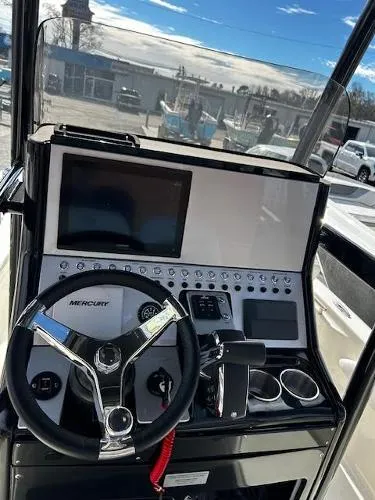 Slide: The Image of 2024 ShearWater 250 SS Carolina boat on trailer, parked near marina under cloudy sky. - 3