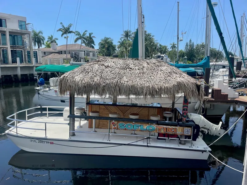 Slide: The Image of Tiki-themed Beachcat boat docked in marina, featuring a thatched roof and tropical decor. - 2