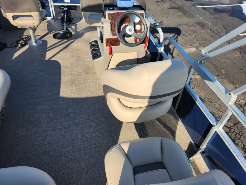 Slide: The Image of 2023 Sun Tracker Bass Buggy 18 DLX pontoon boat interior with beige seating and steering console. - 18
