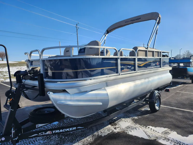 Slide: The Image of 2023 Sun Tracker Bass Buggy 18 DLX pontoon boat on trailer, parked outdoors. - 5
