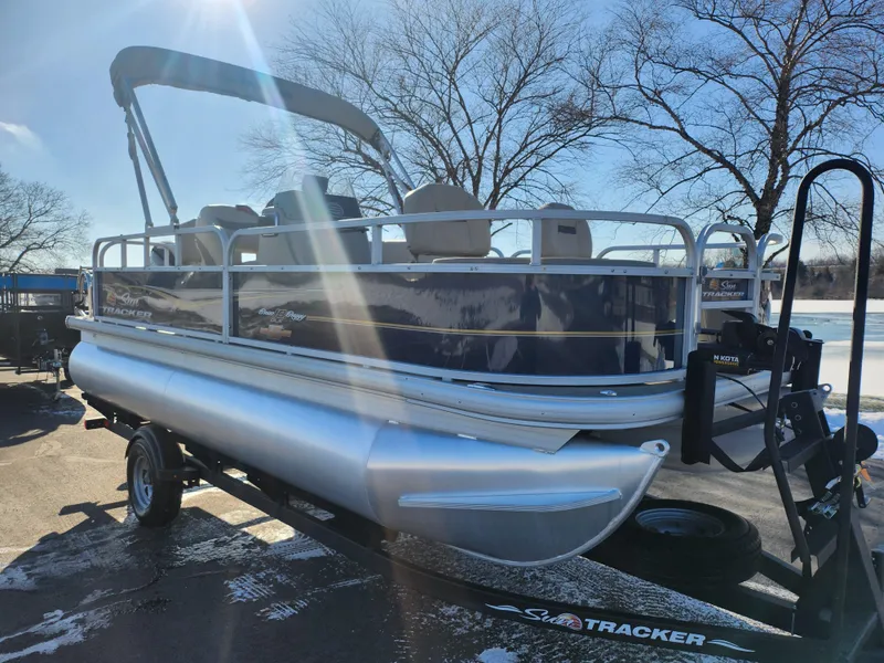 Slide: The Image of 2023 Sun Tracker Bass Buggy 18 DLX pontoon boat on trailer, parked outdoors. - 8
